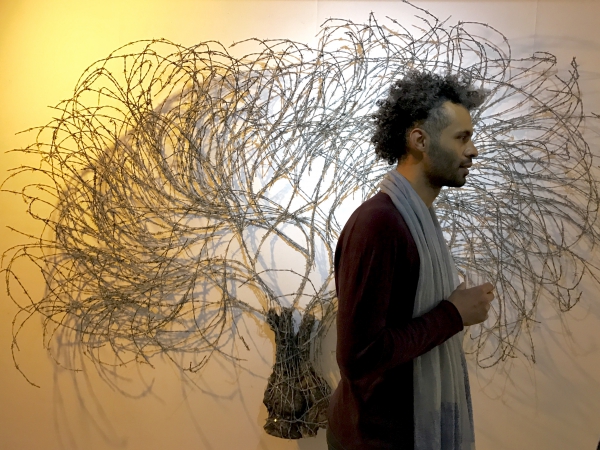 L'artiste palestinien Abdul Rahman Katanini, lors du vernissage de son exposition Resilience à la galerie Analix Forever, soit une série d'oliviers avec du fil de fer barbelé comme frondaison.