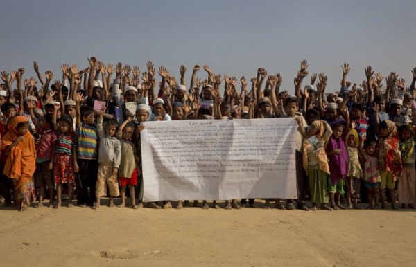 Refugees raise their hands to shout that they will not go back.