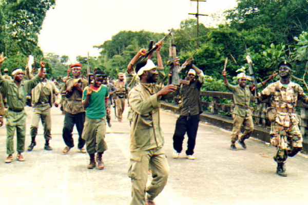 Des combattants de l'ULIMO exécutent une danse guerrière sur un pont, près de Monrovia le 2 septembre 1992