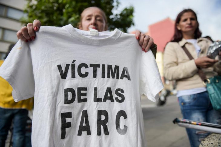 Una mujer sostiene una camiseta en la que se lee "Víctima de las FARC"