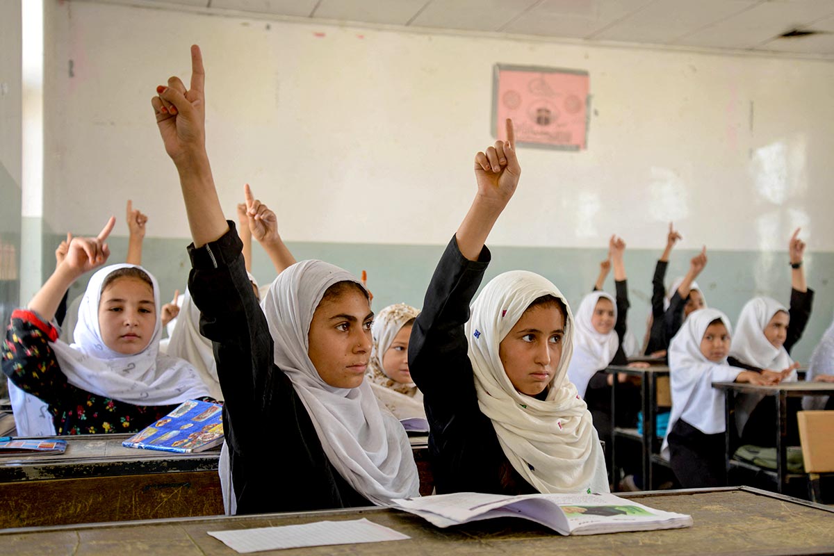 En Afghanistan, des jeunes filles voilées lèvent le doigt dans une salle de classe.
