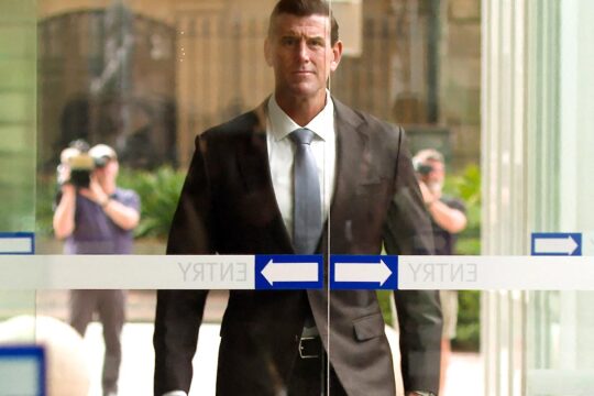 Ben Roberts-Smith, ancien membre des forces spéciales australiennes, est accusé de crimes de guerre en Afghanistan. Photo : Roberts-Smith s'approche de l'entrée d'un tribunal en Australie, en costume pendant que des caméras le filment.