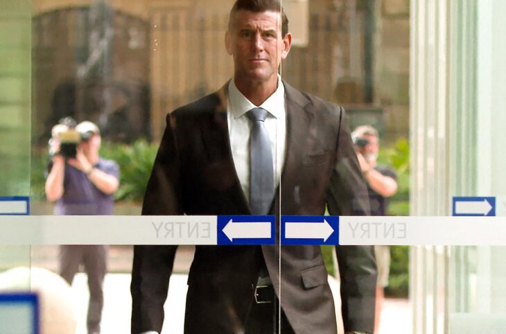 Ben Roberts-Smith, ancien membre des forces spéciales australiennes, est accusé de crimes de guerre en Afghanistan. Photo : Roberts-Smith s'approche de l'entrée d'un tribunal en Australie, en costume pendant que des caméras le filment.