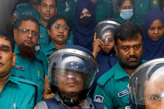 Au Bangladesh, Farzana Rupa et Mozammel Babu, deux journalistes, ont été arrêtés et accusés de crimes contre l'humanité. Photo : de nombreux policiers entourent deux journalistes.