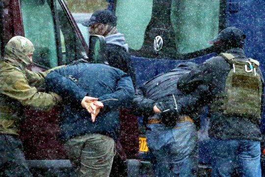 The International Criminal Court (ICC) is launching a thorough investigation in Belarus into alleged crimes against humanity committed against political opponents (deportations). Photo: two protesters are handcuffed, with their hands behind their backs and their backs bent, and are being led away by Belarusian police.