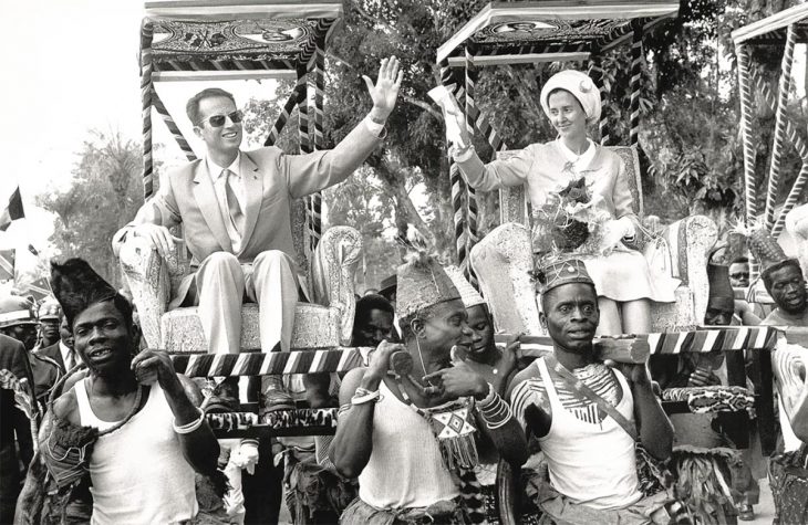 Belgian Colonial Past - Black and white photo in which King Baudouin and Queen Fabiola of Belgium are sitting on armchairs carried by Congolese in traditional dress.