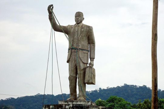 Statue représentant Rumben Um Nyobè le bras levé, avec une malette dans l'autre main