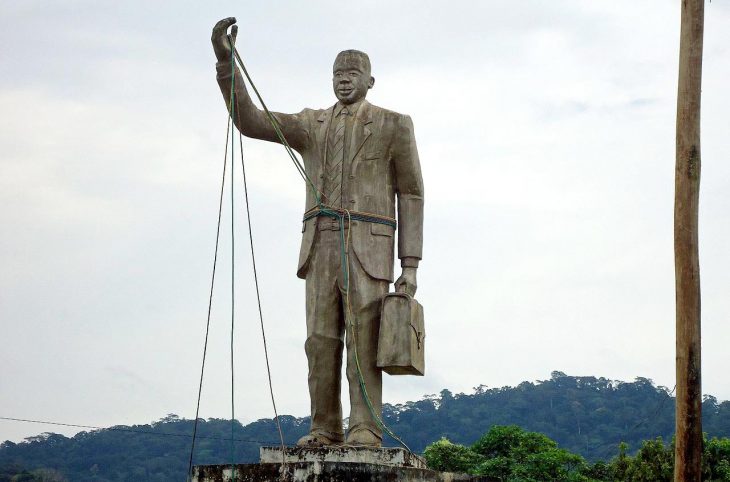 Statue représentant Rumben Um Nyobè le bras levé, avec une malette dans l'autre main