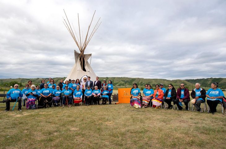 Prime Minister Justin Trudeau, Chief Cadmus Delorme and Saskatchewan Premier Scott Moe stand for a photograph with residential school survivors following a ceremony at the site of a former residential school in Cowessess First Nation, Sask, July 6, 2021.