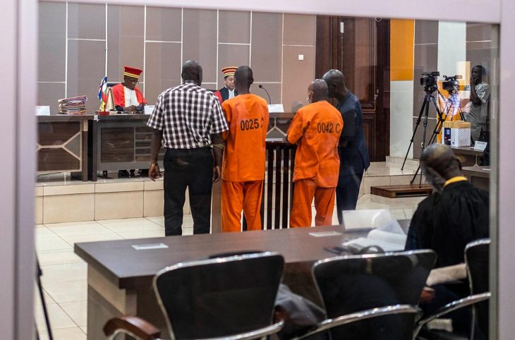 Two detainees in orange suits stand before judges of the Special Criminal Court (SCC) during their trial in Bangui, Central African Republic. They are accused of war crimes and crimes against humanity.