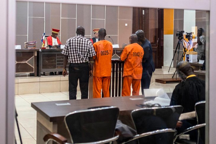 Two detainees in orange suits stand before judges of the Special Criminal Court (SCC) during their trial in Bangui, Central African Republic. They are accused of war crimes and crimes against humanity.