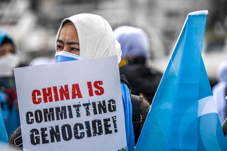 A veiled protester holds a sign that reads "China is committing genocide!"