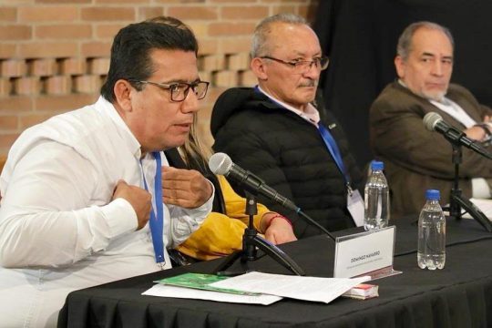 A man (Domingo Navarro) speaks into a microphone during a hearing of the Jurisdicción Especial para la Paz (JEP) in Colombia.