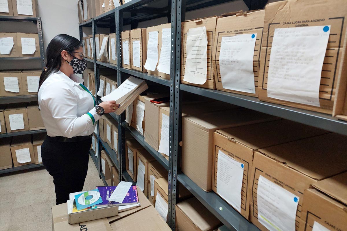 A woman consults documents filed in many boxes.