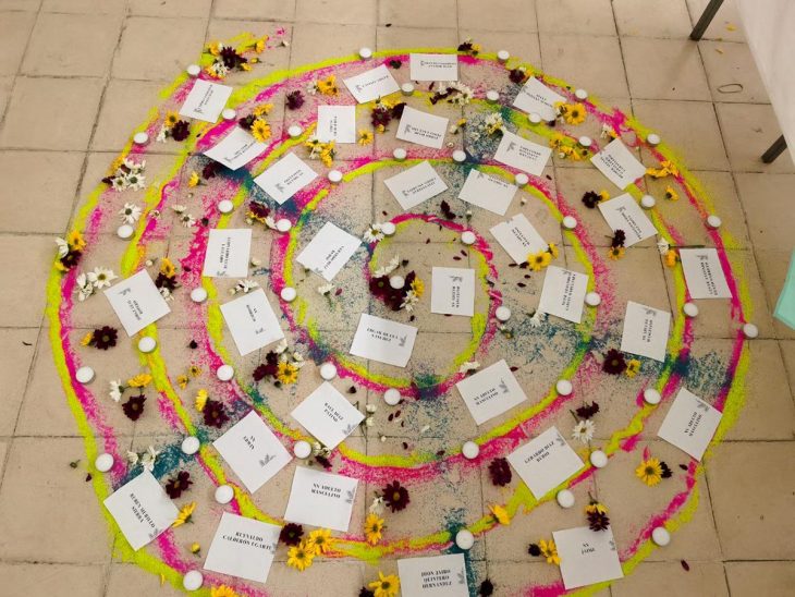 Una instalación en memoria de las víctimas de la masacre de La Gabarra, en Colombia: una espiral de colores hecha de velas, flores y hojas de papel en las que se han escrito los nombres de las víctimas.