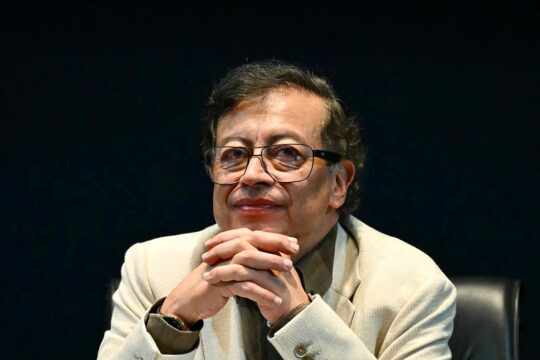 Gustavo Petro, Colombia’s former president, has asked the International Criminal Court (ICC) to reopen an investigation into Colombia, just before stepping down from office in early August 2026. What impact will this have on local transitional justice? Photo: Petro, seated at a conference, appears to be waiting for something, smiling with his hands clasped.