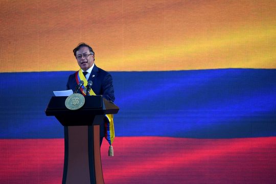 The new president of Colombia, Gustavo Petro, delivers a speech on a podium. In the background: the Colombian flag.