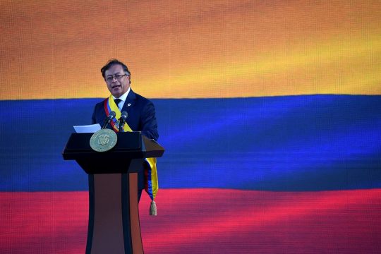 Le nouveau président de Colombie, Gustavo Petro, prononce un discours sur une estrade. En arrière-plan : le drapeau colombien.