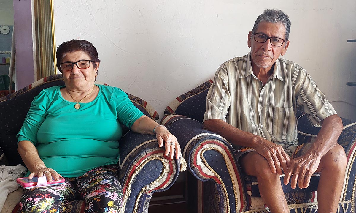 Paulina Hernández y Cristo Quintero están sentados en su casa en sillones de colores.