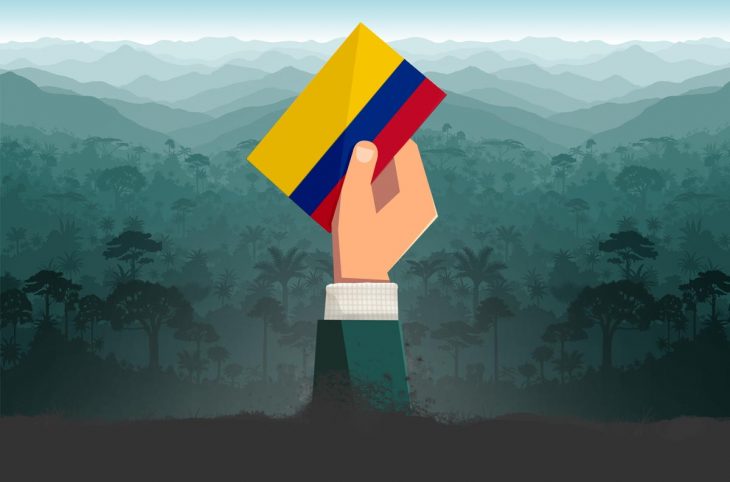 Una mano que sobresale del suelo sostiene una papeleta con los colores de la bandera colombiana