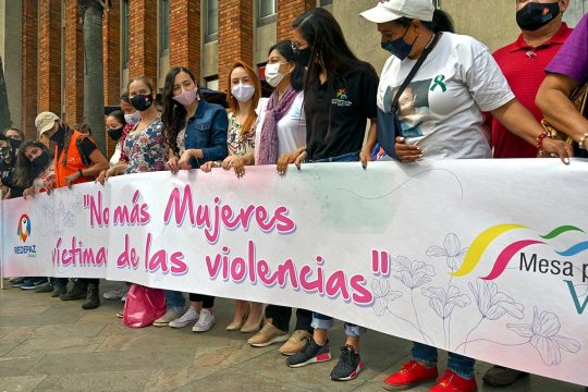 Unas mujeres sostienen una pancarta con las palabras "No más mujeres víctimas de la violencia" en español.