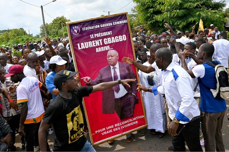 Ivorians around a poster of Laurent Gbagbo in anticipation of his return home