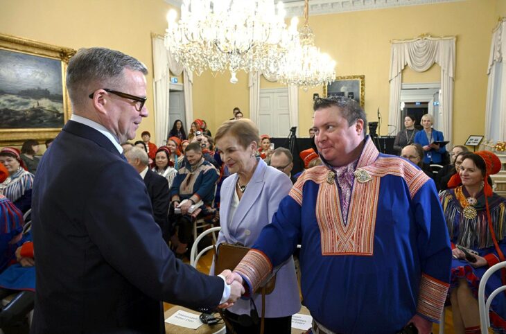 In Finland, Prime Minister Petteri Orpo and Tuomas Aslak Juuso (from the Sami Parliament) met to receive the Truth and Reconciliation Commission's final report. Photo: Orpo and Juuso shake hands in a packed reception hall. Juuso is wearing traditional Sami clothing.