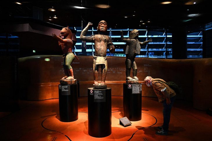 A visitor to the Quai Branly Museum observes 3 statues from the royal treasures of Abomey.