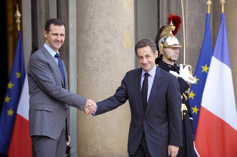 Syria / France - When French justice rethinks the impunity of heads of state. Photo: On the steps of the Elysée Palace in Paris, Nicolas Sarkozy and Bashar al-Assad smile as they shake hands.