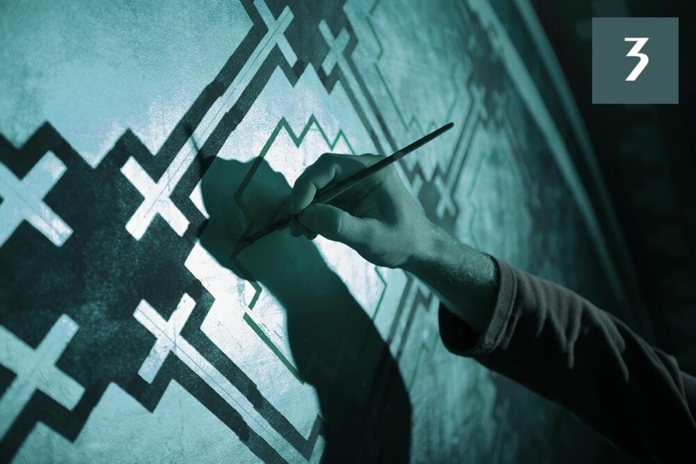 Réparations pour les victimes de l'Église de France. Photo : un peintre utilise un outil pour rénover une peinture murale où plusieurs croix catholiques sont représentées.
