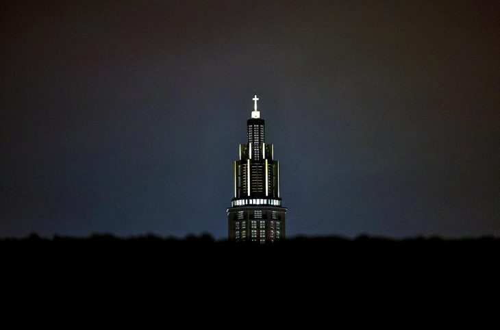 A church seen at night in France with some ornaments (a cross at the top) illuminated.