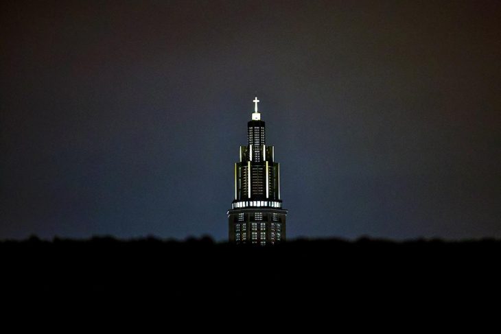 A church seen at night in France with some ornaments (a cross at the top) illuminated.