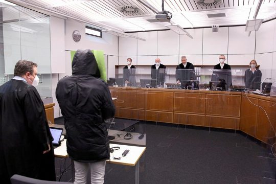 Bai Lowe, de dos (en manteau avec capuche) lors de son procès à Celle (Allemagne), fait face aux juges.