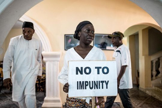 In Gambia, a woman holds a sign saying 