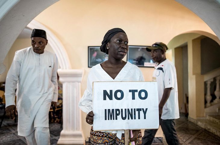 In Gambia, a woman holds a sign saying "no to impunity".