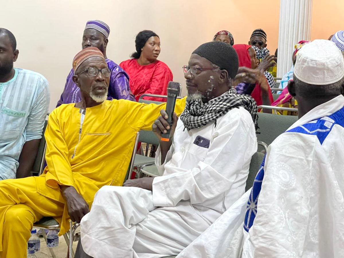 An elder (seated, holding a microphone) addresses the prosecutor of the Special Court for The Gambia.