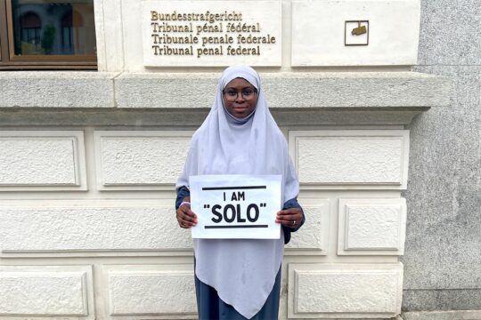 Sonko trial in Switzerland: former Gambian Interior Minister Ousman Sonko found guilty of crimes against humanity, including the murder of Solo Sandeng. Photo: Fatoumata Sandeng, daughter of Ousman Solo Sandeng, holds a sign reading “I am Solo”.