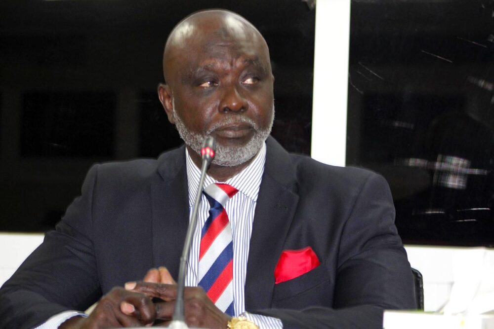 In The Gambia, Tamsir Jasseh served under the former (fugitive) dictator Yayya Jammeh. He is testifying in a national trial against one of Jammeh’s “junglers” (militiamen): Sanna Manjang. Photo: Jasseh, in a suit, speaks into the microphone at the The Gambia Truth and Reconciliation Commission (TRRC).