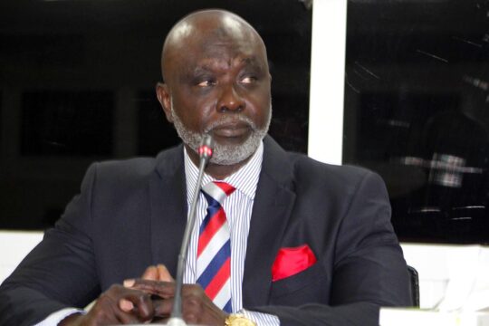 In The Gambia, Tamsir Jasseh served under the former (fugitive) dictator Yayya Jammeh. He is testifying in a national trial against one of Jammeh’s “junglers” (militiamen): Sanna Manjang. Photo: Jasseh, in a suit, speaks into the microphone at the The Gambia Truth and Reconciliation Commission (TRRC).