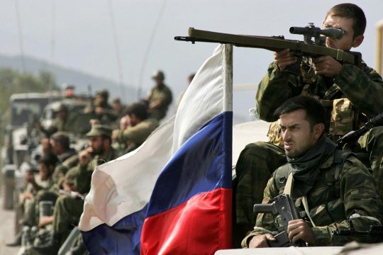 Russian soldiers (including a sniper) in Georgia. A Russian flag flutters in the wind.