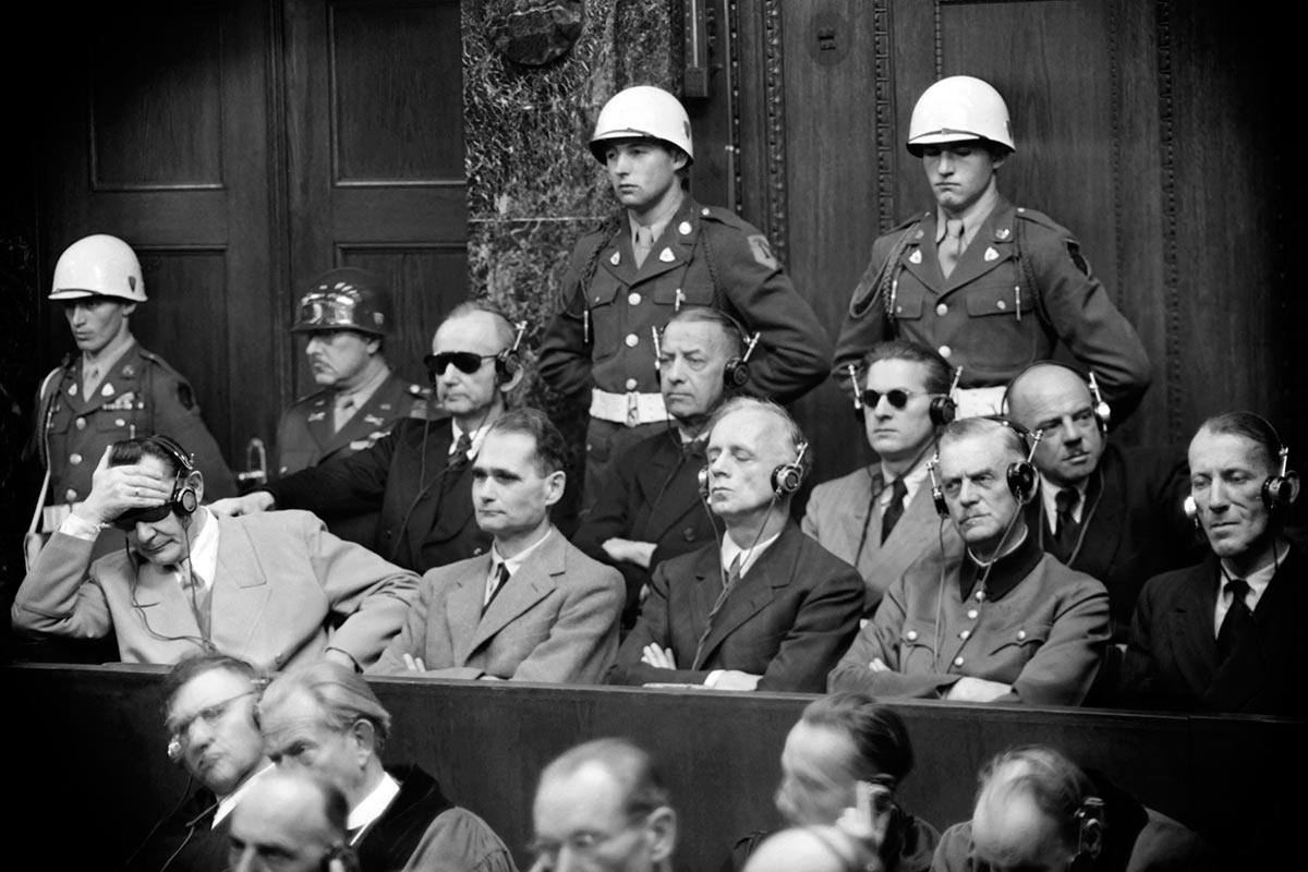 Des accusés de l'ancien régime nazi lors du procès de Nuremberg en Allemagne, encadrés par la police militaire.