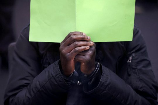 Baboucar "Bai" Lowe, a Gambian accused of participating in the crimes of the "Junglers" in Gambia, hides behind a piece of paper during his trial in Germany, in Celle.