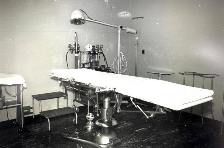 Photo en noir et blanc d'un lit d'hôpital (type table d'opération) dans les années 60-70.