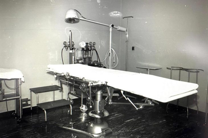 Photo en noir et blanc d'un lit d'hôpital (type table d'opération) dans les années 60-70.