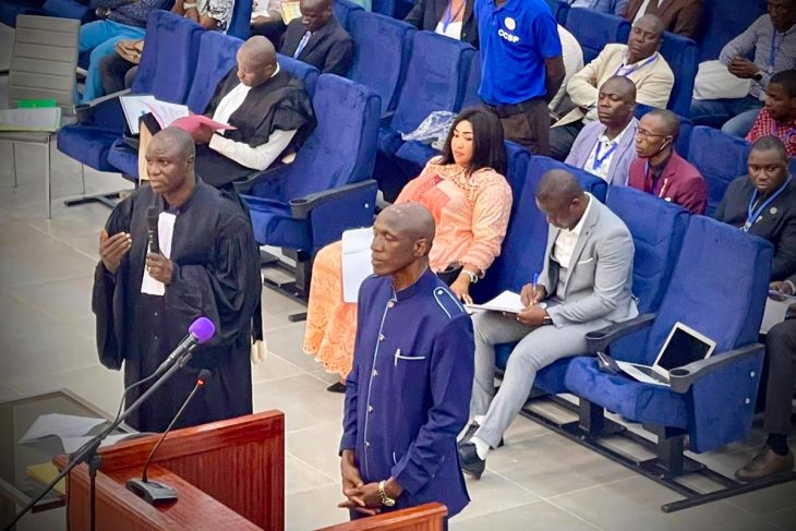 Moussa Tiegboro Camara stands on the stand next to his lawyer during his trial. He is accused of participating in the Conakry Stadium massacre in Guinea.