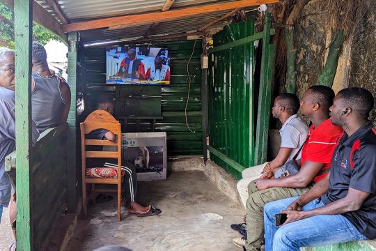Des Guinéens regardent à la télévision une retransmission du procès du 28 septembre à Conakry.