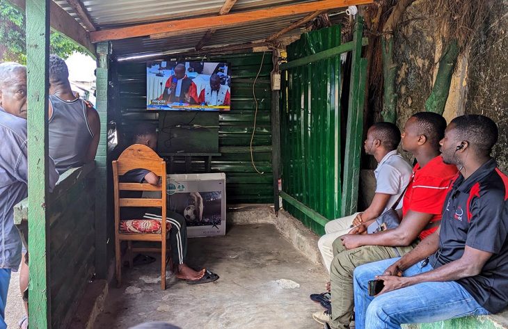 Des Guinéens regardent à la télévision une retransmission du procès du 28 septembre à Conakry.