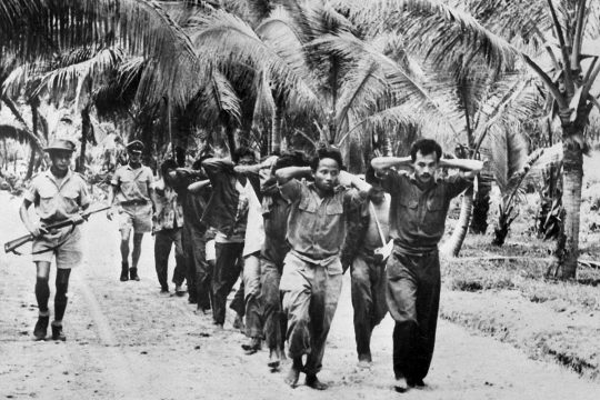 Des prisonniers indonésiens (mains sur la tête) sont escortés par des soldats néerlandais
