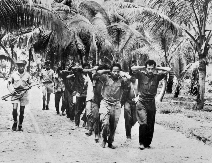 Indonesian prisoners (hands on head) are escorted by Dutch soldiers