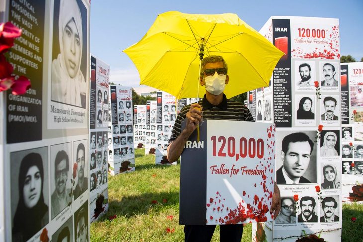 Activist in front of thousands of photos of victims of the 1988 massacres in Iran